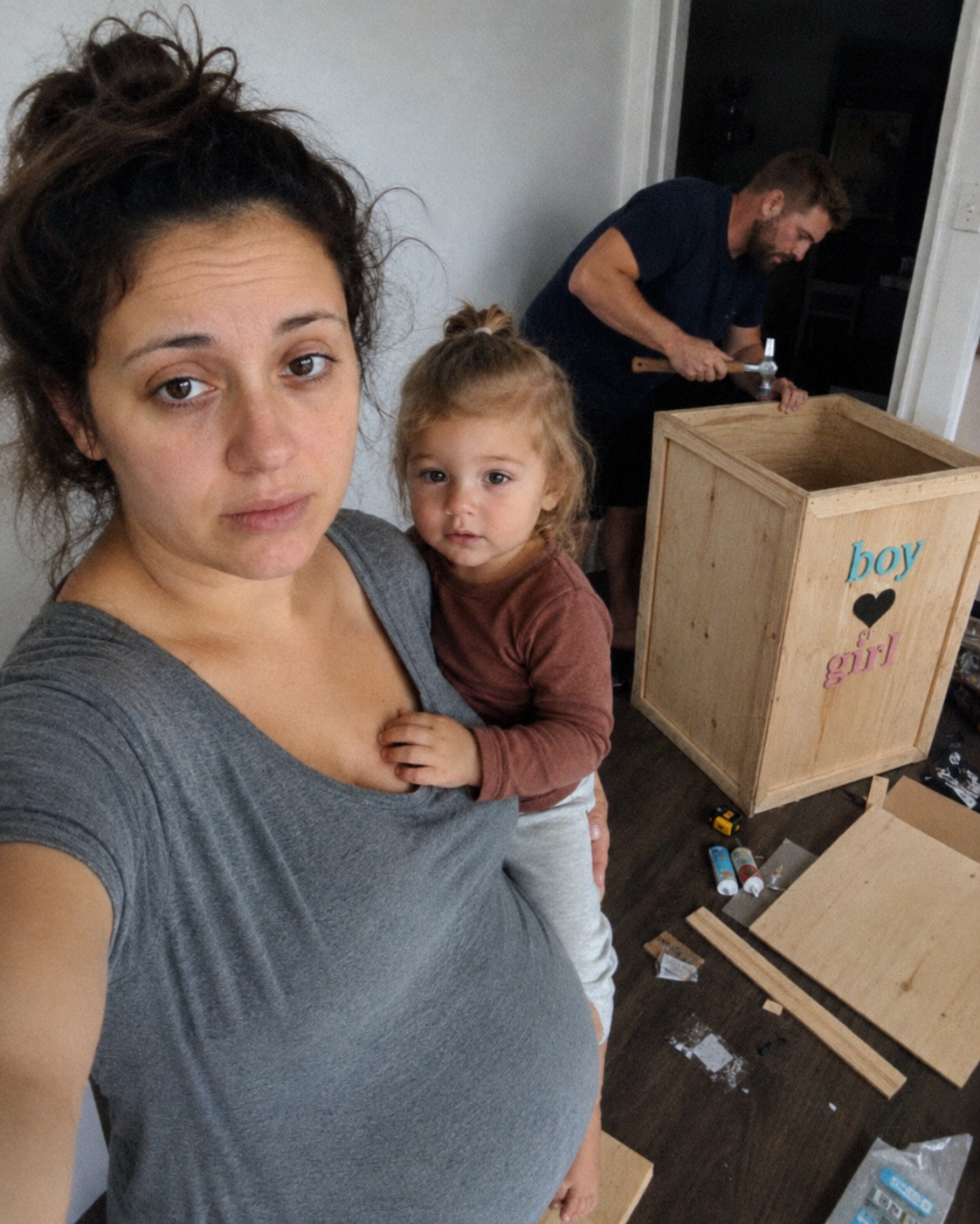 Pregnant mum with toddler near a DIY reveal box being built